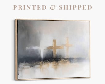 May include: Abstract art print featuring three crosses in gold and white against a gray and beige background. The artwork is framed in a light wood frame. The text "PRINTED & SHIPPED" is at the top of the image.