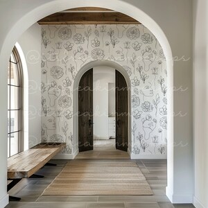 Puede incluir: Un pasillo con una pared blanca con un dise&ntilde;o de papel tapiz de arte de l&iacute;nea en blanco y negro de flores y caras. El papel tapiz es un dise&ntilde;o moderno y minimalista. El pasillo tiene un banco de madera y una alfombra.
