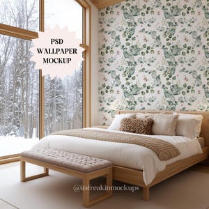 May include: A bedroom mockup featuring a wooden bed frame, bench, and large window. The bed has white bedding, a tan throw, and decorative pillows. The wallpaper has a green and white eucalyptus pattern. The text on the image says "PSD WALLPAPER MOCKUP".