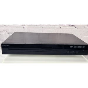May include: Black Insignia DVD player with a disc tray and control buttons. The DVD player has the Insignia logo on the left side and DVD, CD, and Dolby symbols on the right side. The player is on a white surface.