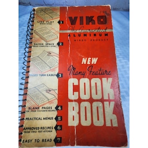 May include: Vintage cookbook with a red and cream cover, spiral-bound. The cover features the text "VIKO The Guaranteed Aluminum" and "NEW Many Feature COOK BOOK." It highlights features like "Lies Flat," "Saves Space," and "Easy to Read."