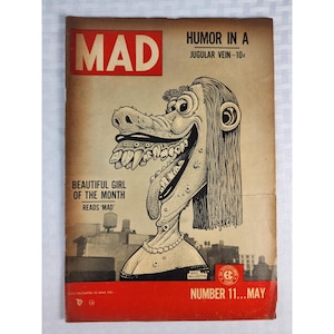 May include: A vintage MAD magazine cover, number 11 from May, featuring a black and white caricature of a woman with exaggerated features, long hair, and a pearl necklace. The cover includes the text MAD, HUMOR IN A JUGULAR VEIN, and BEAUTIFUL GIRL OF THE MONTH.