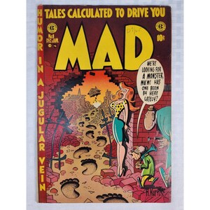May include: A vintage MAD comic book issue number 8, dated Dec-Jan, featuring a colorful cover illustration of a woman and two men standing by a brick wall with large footprints leading toward a house. The text reads Tales Calculated to Drive You.