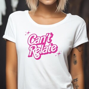 May include: White t-shirt with a pink graphic that says "Can't Relate" in a retro font.