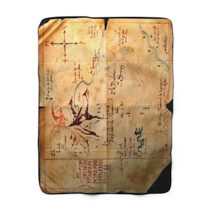 Puede incluir: Una manta polar con un mapa detallado con ilustraciones de un dragón, montañas y texto. El mapa es en tonos marrones y beige, con acentos rojos y verdes. La manta tiene un borde negro.