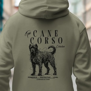 Puede incluir: Sudadera con capucha verde oliva con un gráfico negro de un perro Cane Corso y el texto "The Cane Corso Collective". El gráfico incluye las palabras "Powerful, Protective, Loyal".