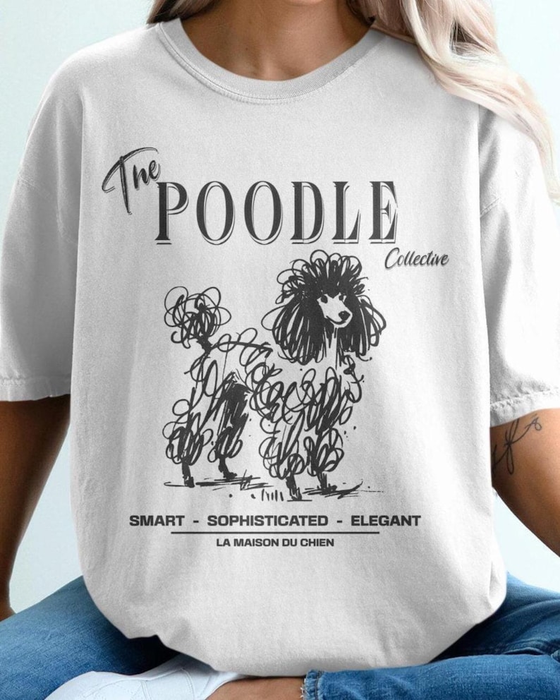 May include: A white t-shirt with black text that reads 'The Poodle Collective' and a black and white illustration of a poodle. The text below the illustration reads 'Smart - Sophisticated - Elegant' and 'La Maison du Chien.'