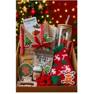 May include: A Christmas-themed gift box filled with festive items. Includes a glass tumbler, red pen, stickers, a red and green sock, a candy cane, and a small bag of hot chocolate. The box is decorated with a red bow and Christmas-themed stickers.