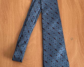 May include: A blue patterned tie with a geometric design. The pattern is made up of small white and red circles and lines.
