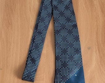May include: A dark blue tie with a white and red polka dot pattern. The tie has a solid dark blue tip with the letter "N" in white.