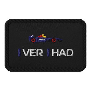 Op de afbeelding: Zwart geborduurde patch met een blauwe raceauto, rode wielen en gele accenten. De witte tekst "I VER | HAD" is eronder geborduurd. De patch heeft een zwarte rand.