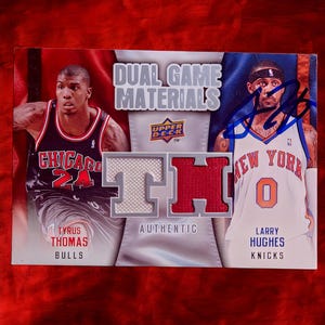 May include: A basketball trading card featuring Tyrus Thomas of the Chicago Bulls and Larry Hughes of the New York Knicks. The card includes the text "Dual Game Materials" and "Authentic".