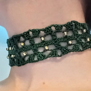 May include: A green crocheted choker necklace with gold beads.