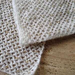 May include: White crocheted shawl with gold beads. The shawl is folded in half and the edges are visible.