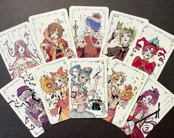 May include: A collection of ten rectangular playing cards arranged in a fan shape, each featuring a unique, colorful anime-style illustration of a character with intricate line work, decorative borders, and various thematic elements like flowers and magic.