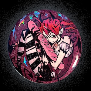 May include: A circular pin featuring a glittery magenta background with a stylized illustration of a character with red hair, black and white striped stockings, and a small bell collar, surrounded by holographic blue star accents.