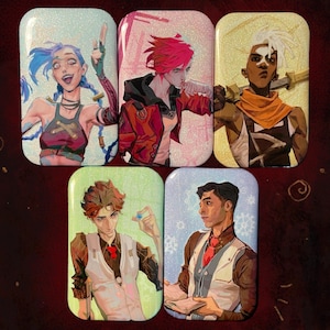 May include: Set of five rectangular character art pins. The pins feature illustrations of characters with varying hair colors and outfits. The backgrounds are light blue, green, and gold. The characters are in various poses, some holding objects.
