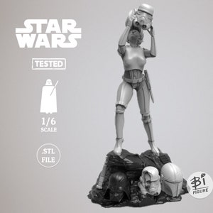 May include: A grey 3D printed model of a female Star Wars character holding a Stormtrooper helmet. The model is standing on a rock base with other helmets, including Darth Vader's, a Clone Trooper's, and a Mandalorian's.