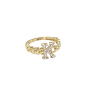 May include: A gold ring with a chain design and a letter K set with clear stones.