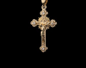Precioso colgante grande de cruz color oro que representa a Jesús en la cruz, engastado con pequeños diamantes de imitación y con cadena ajustable. Colección