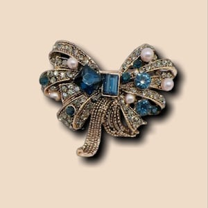 Magnifique grande broche nœud couleur or bronze sertie de cristal ciselés bleus roi et sertie de petites perles blanc nacré vintage