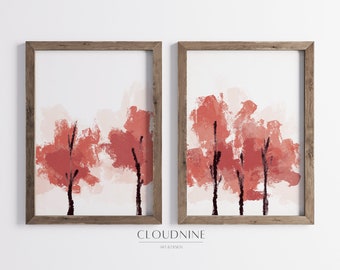 May include: Two framed abstract art prints with a watercolor-like style. The prints feature a landscape of red and pink trees against a white background. The frames are a rustic brown wood.