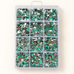 Puede incluir: Un contenedor de almacenamiento de plástico transparente con doce compartimentos individuales llenos de pequeñas piezas de espejo reflectantes en varias formas geométricas, incluyendo gotas, diamantes y círculos, todas con un reverso de color verde vibrante.