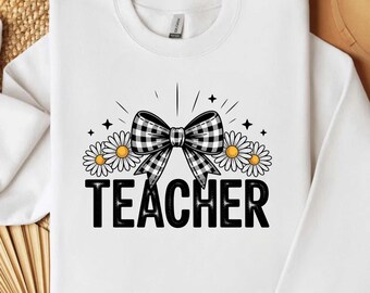 May include: White sweatshirt with a black and white checkered bow, daisies, and the word "TEACHER" in bold black letters. The design includes star accents and radiating lines, creating a cheerful and educational theme.