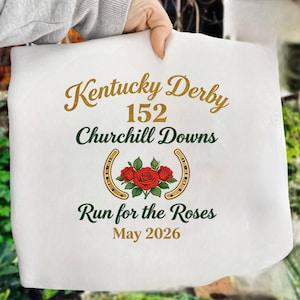 May include: White fabric with gold and green text that reads "Kentucky Derby 152 Churchill Downs Run for the Roses May 2026." The design includes a horseshoe and red roses.