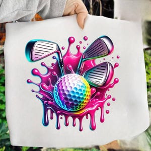 May include: A white tote bag featuring a colorful golf ball and golf clubs. The golf ball is a rainbow of colors, and the clubs are silver and black. The design includes a vibrant pink and purple splash effect, creating a dynamic and eye-catching image.