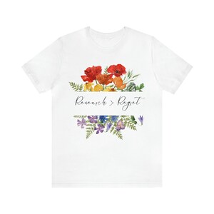 May include: White t-shirt featuring a floral design and the text "Research > Regret" printed on the front.