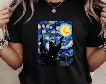 Peut inclure: T-shirt noir avec un motif coloré d'un chat noir tendant la patte vers une lune et des étoiles en croissant, sur fond de ciel nocturne bleu et jaune tourbillonnant. Le design rappelle "La Nuit étoilée" de Van Gogh.