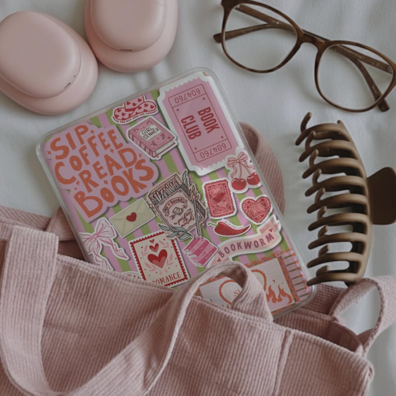 May include: A pink corduroy tote bag with a clear phone case decorated with stickers that read "Sip Coffee Read Books". Other items include pink earbuds, brown glasses, and a brown hair clip. The theme is centered around reading and books.