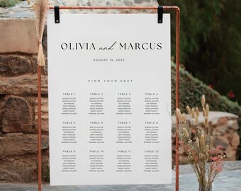 Puede incluir: Un cartel de asignación de asientos de boda blanco con un marco de cobre. El cartel enumera los nombres de los invitados asignados a cada número de mesa. El texto en la parte superior dice "Olivia y Marcus, 14 de agosto de 2023, Encuentra tu asiento."
