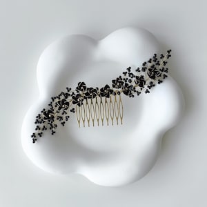 Puede incluir: Peine de pelo floral negro con dientes de metal dorado y cuentas negras. El peine está sobre una superficie blanca en forma de nube.