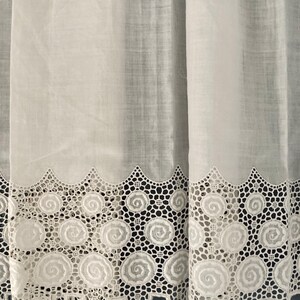 Puede incluir: Cortinas blancas transparentes con un borde de encaje festoneado decorativo. El encaje presenta un patr&oacute;n repetitivo de dise&ntilde;os en espiral. Las cortinas est&aacute;n hechas de una tela ligera, lo que permite que la luz se filtre.