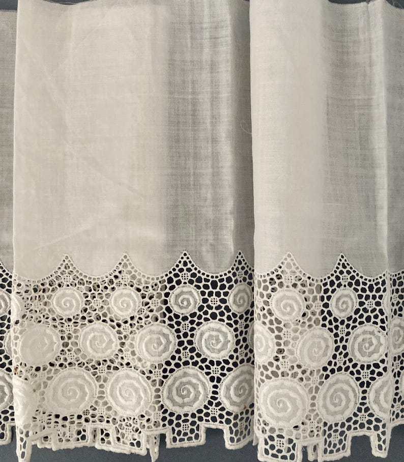 Puede incluir: Cortinas blancas transparentes con un borde de encaje festoneado decorativo. El encaje presenta un patr&oacute;n repetitivo de dise&ntilde;os en espiral. Las cortinas est&aacute;n hechas de una tela ligera, lo que permite que la luz se filtre.