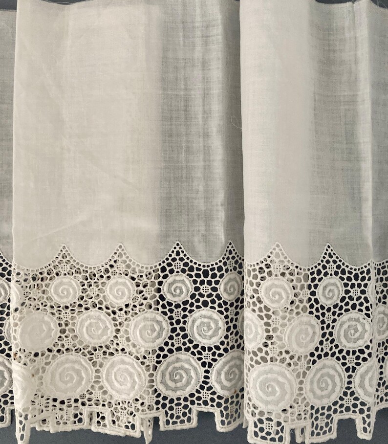 Puede incluir: Cortinas blancas transparentes con un borde de encaje festoneado decorativo. El encaje presenta un patr&oacute;n repetitivo de dise&ntilde;os en espiral. Las cortinas est&aacute;n hechas de una tela ligera, lo que permite que la luz se filtre.