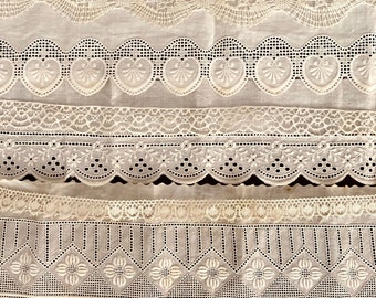 May include: Five different white lace trims with intricate patterns. The trims are arranged in a stack, with the top trim being the most delicate and the bottom trim being the most elaborate.
