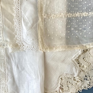 Può includere: Una collezione di fazzoletti bianchi e color avorio con varie texture, tra cui tessuto trasparente con pois ricamati, ricami floreali e bordi in pizzo intricati. I tessuti sono sovrapposti, mostrando diversi motivi e bordi distinti.