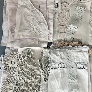 Könnte beinhalten: Eine Sammlung von Vintage-Textilien in verschiedenen Weiß-, Creme- und Blassrosatönen. Die Auswahl umfasst Spitzenbesätze, Deckchen und bestickte Stücke, die komplizierte Muster und Texturen aufweisen. Die Stoffe scheinen Leinen und Baumwolle zu sein.