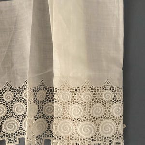 Puede incluir: Primer plano de cortinas de encaje blanco con un delicado dise&ntilde;o en espiral. Las cortinas est&aacute;n hechas de una tela transparente, que permite el paso de la luz. El intrincado borde de encaje a&ntilde;ade un toque de elegancia.