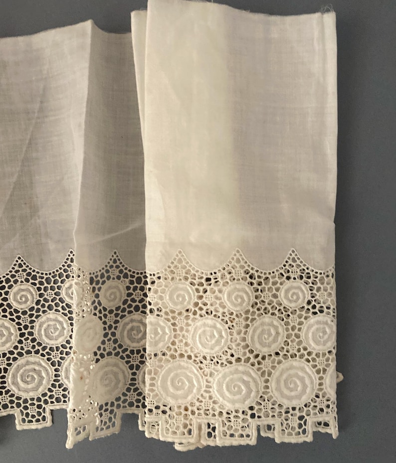 Puede incluir: Primer plano de cortinas de encaje blanco con un delicado dise&ntilde;o en espiral. Las cortinas est&aacute;n hechas de una tela transparente, que permite el paso de la luz. El intrincado borde de encaje a&ntilde;ade un toque de elegancia.