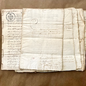 Op de afbeelding: Een stapel verouderde, gebroken witte papieren documenten met handgeschreven tekst en sierlijke kalligrafie. Sommige pagina's bevatten zegels en stempels. De papieren zijn gevouwen en lijken historische documenten of correspondentie te zijn.