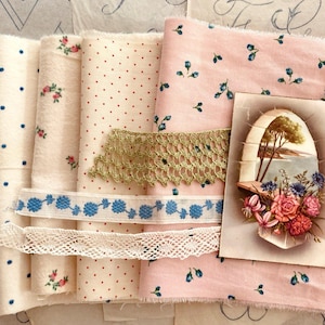 Puede incluir: Una colección de rollos de tela en varios patrones y colores. Las telas incluyen estampados florales, lunares y colores lisos, acentuados con encaje y cinta. Se incluye una postal vintage con un arreglo floral.