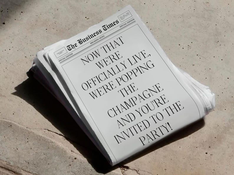 May include: A stack of newspapers with the headline "NOW THAT WE'RE OFFICIALLY LIVE, WE'RE POPPING THE CHAMPAGNE AND YOU'RE INVITED TO THE PARTY!" The newspaper is titled "The Business Times" and is a special edition.