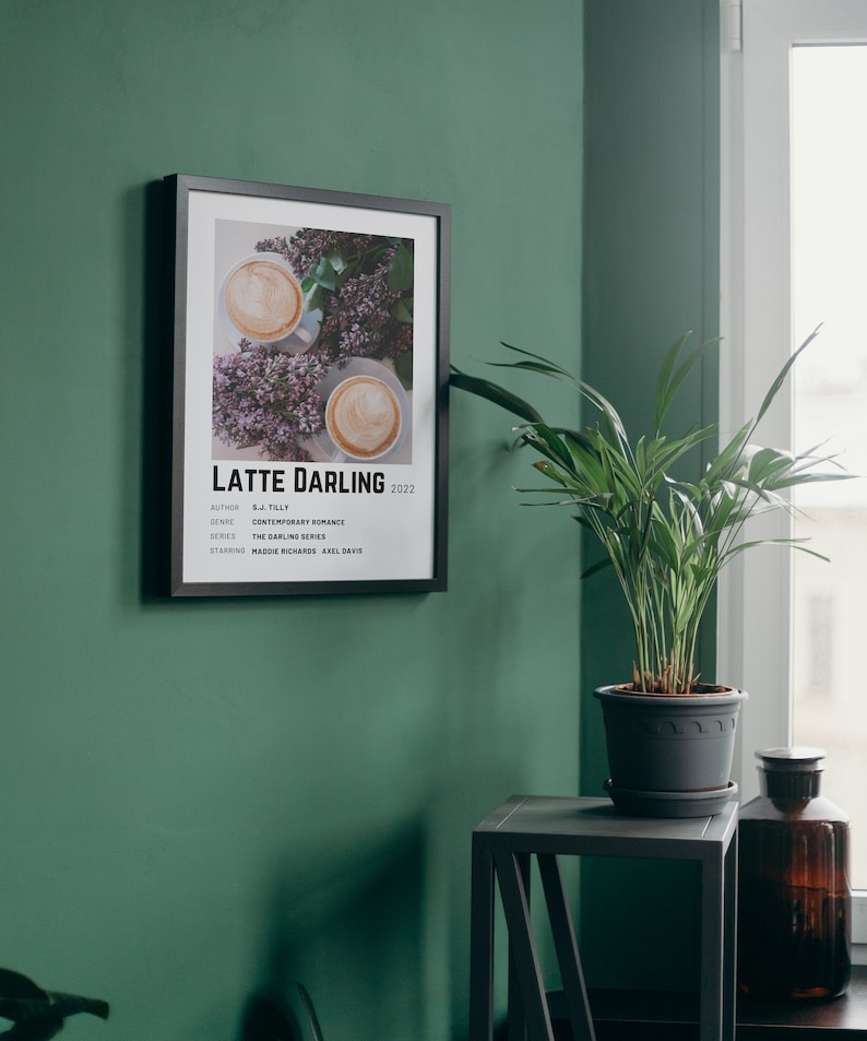 Może przedstawiać: Czarny plakat w ramie z białym tłem i minimalistycznym wzorem. Plakat przedstawia zdjęcie dw&oacute;ch filiżanek kawy z latte art i fioletowymi kwiatami. Tekst na plakacie brzmi "Latte Darling 2022" i zawiera informacje o autorze, gatunku, serii i gł&oacute;wnych aktorach.