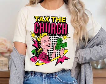 May include: A white t-shirt featuring a graphic print of a woman holding money. The text "Tax the Church" is printed in pink and black lettering.