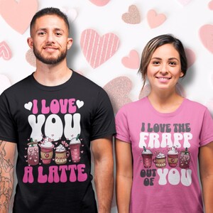 May include: Two t-shirts with a Valentine's Day theme. The black t-shirt has a pink heart and the text "I love you a latte" with a graphic of coffee drinks. The pink t-shirt has the text "I love the frapp out of you" with a graphic of coffee drinks.