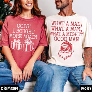 Peut inclure: Deux t-shirts &agrave; manches courtes. L'un est rouge cramoisi avec le texte "OOPS! I BOUGHT MORE AGAIN" et des graphiques de bo&icirc;tes cadeaux. L'autre est ivoire avec le texte "WHAT A MAN, WHAT A MAN, WHAT A MIGHTY GOOD MAN" et un graphique du P&egrave;re No&euml;l.